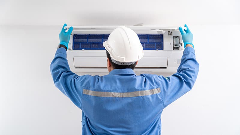 Technicien en train de nettoyer une unité intérieure de climatisation à Paris